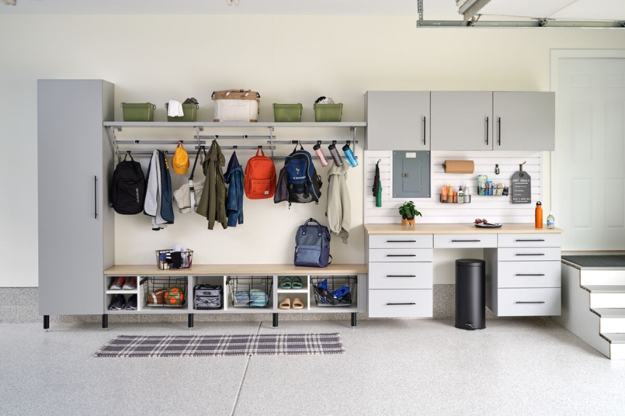 Functional garage entryway with hooks, lockers, benches, and cabinets for coats, backpacks, and cleaning supplies.