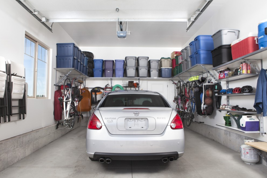Clean two-car garage with wall-mounted shelves, overhead storage bins, and organized sports equipment and bicycles.
