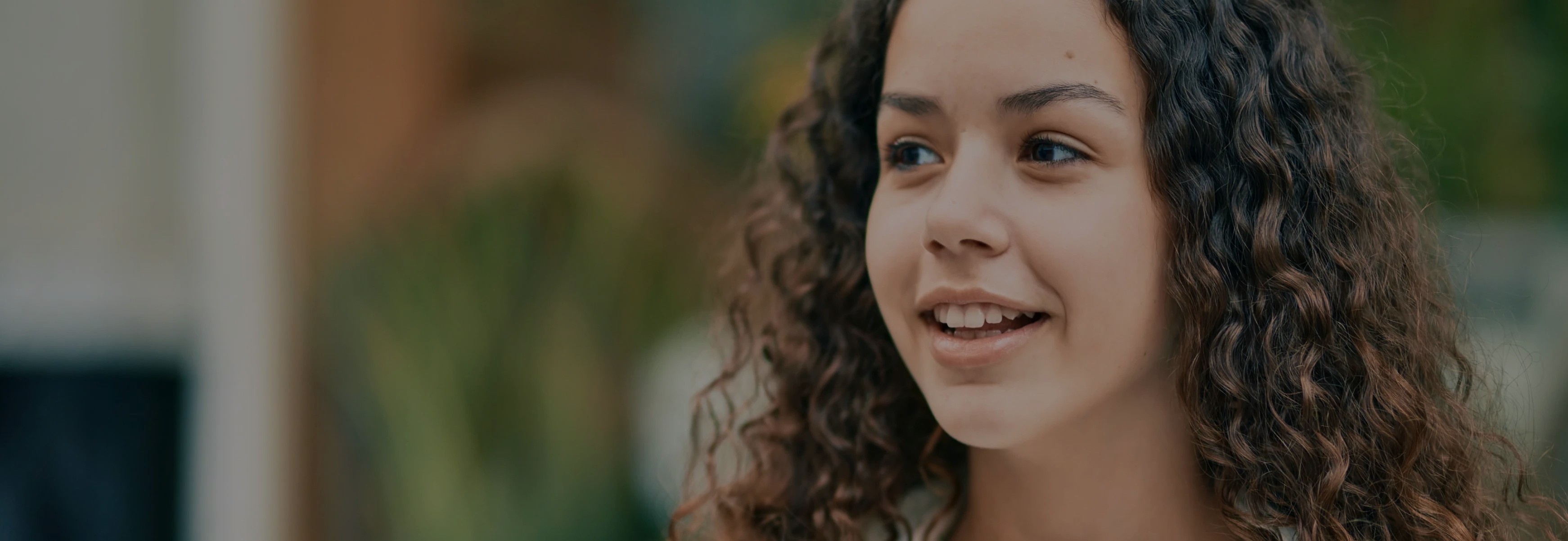 Teenage girl with curly hair smiling during a conversation