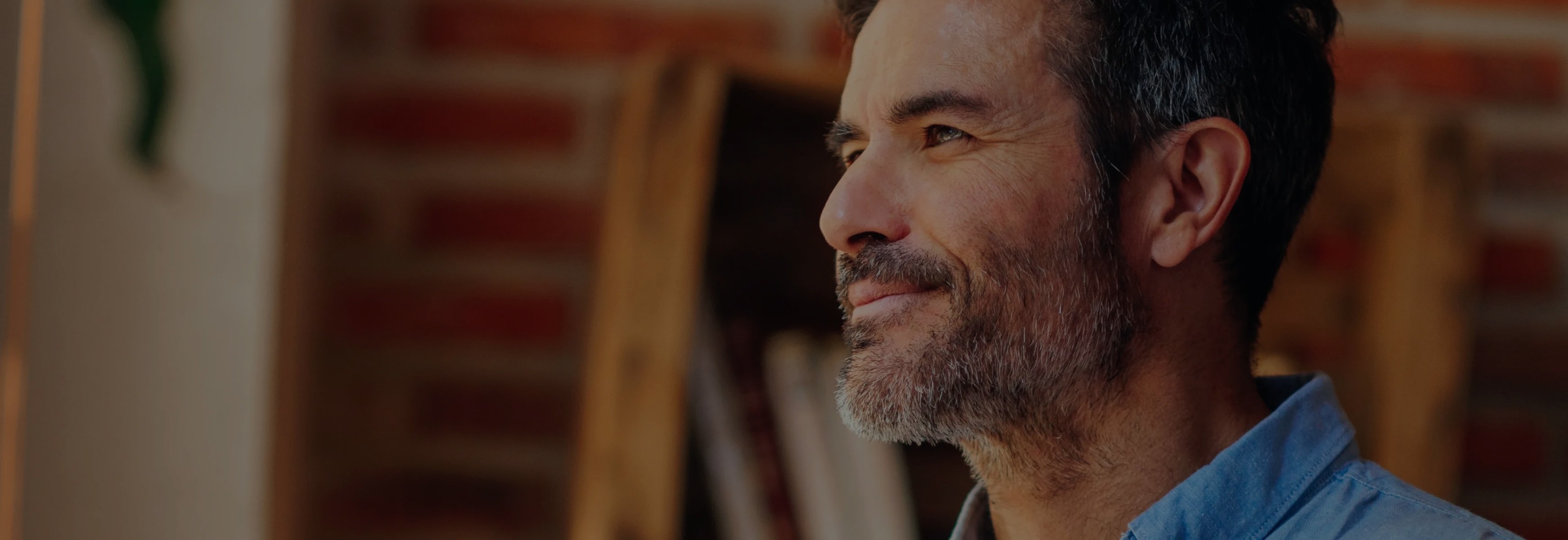 Man in a blue shirt gazing thoughtfully into the distance