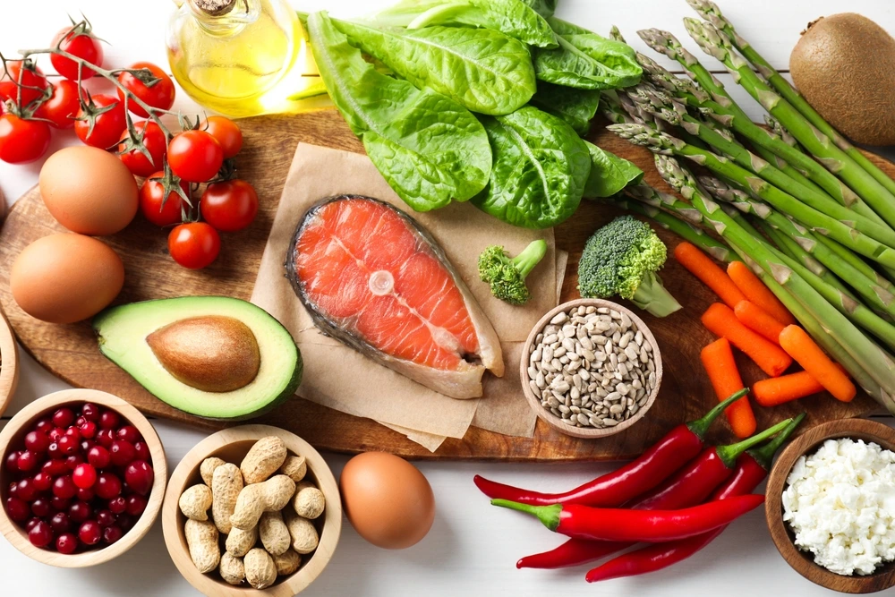 Vielfältige Lebensmittel wie Gemüse, Obst, Fisch, Eier und Nüsse auf einem Holzbrett – gesunde Ernährungspyramide