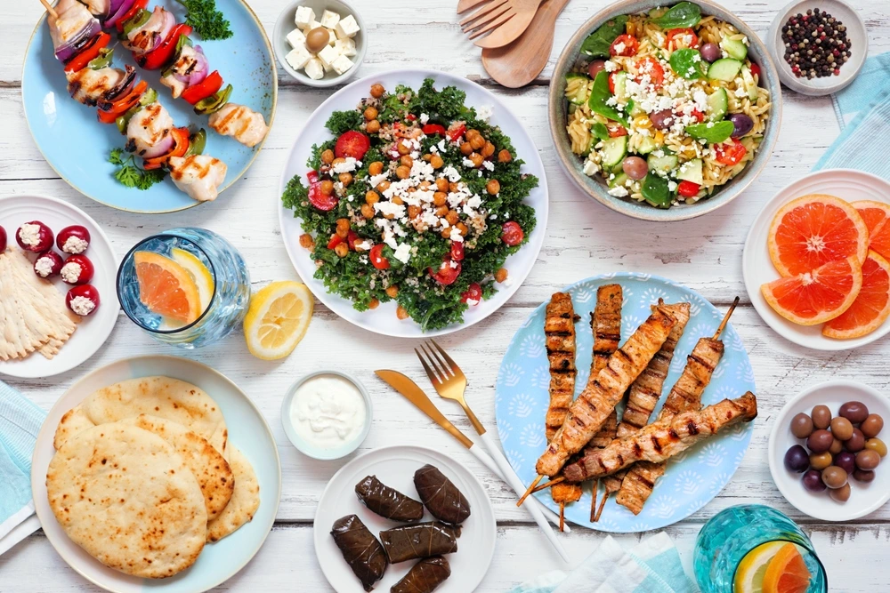 Vielfältige mediterrane Gerichte wie Grillspieße, Salate, Fladenbrot und gefüllte Weinblätter – ein Beispiel dafür, wie ausgewogene Diätformen lecker und abwechslungsreich gestaltet werden können.