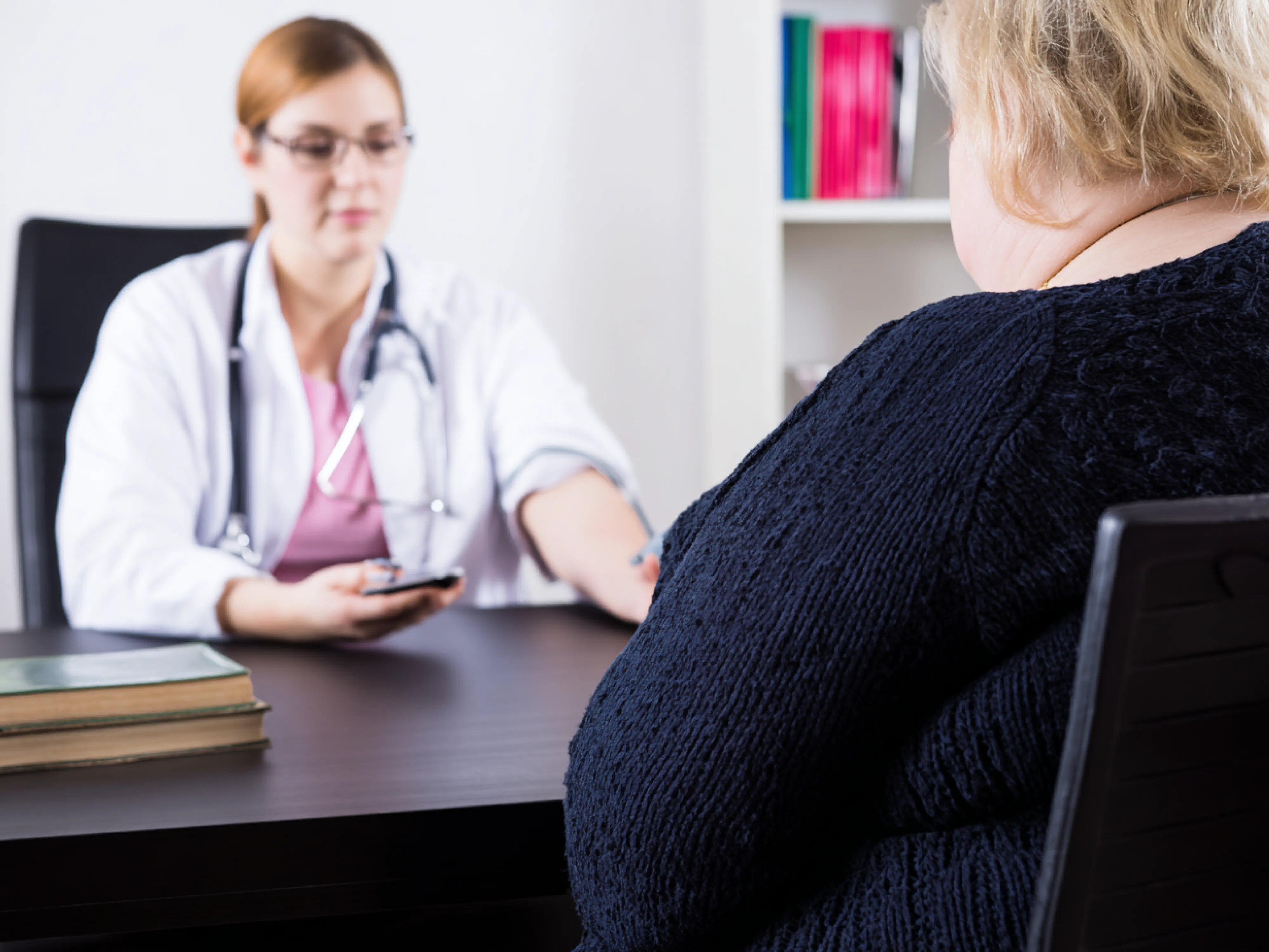 Ärztin misst Blutdruck bei einer Patientin mit Übergewicht während der Diagnose für Adipositas.