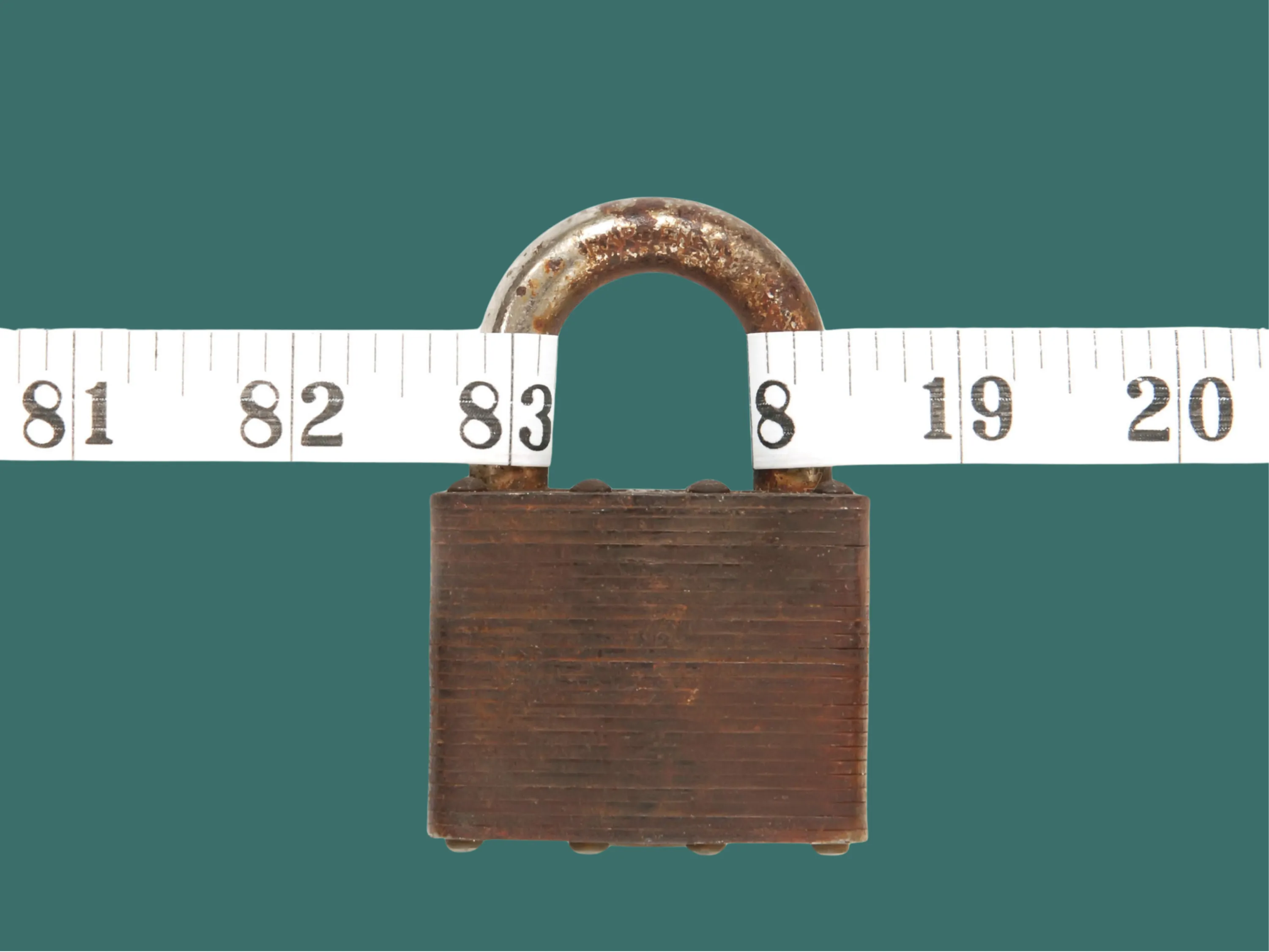 Rostiges Vorhängeschloss, um das ein Maßband mit der Zahl 83 Zentimeter gespannt ist, vor grünem Hintergrund als Symbolbild dafür, wenn das Gewicht stagniert.
