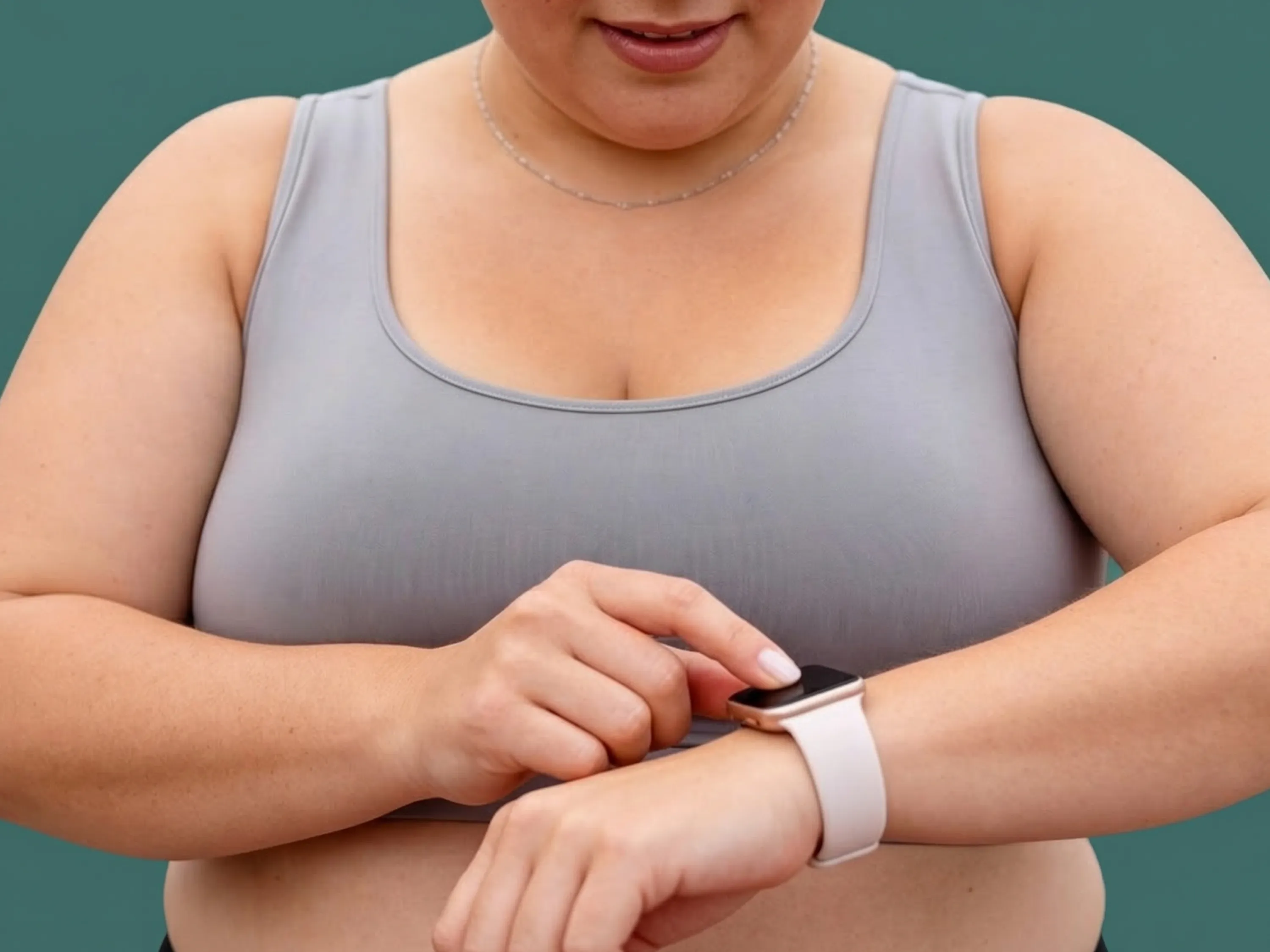 Eine übergewichtige Frau in Sportkleidung bedient eine Smartwatch an ihrem Handgelenk, um ihren Fortschritt beim Abnehmen mit Smartwatch zu verfolgen.