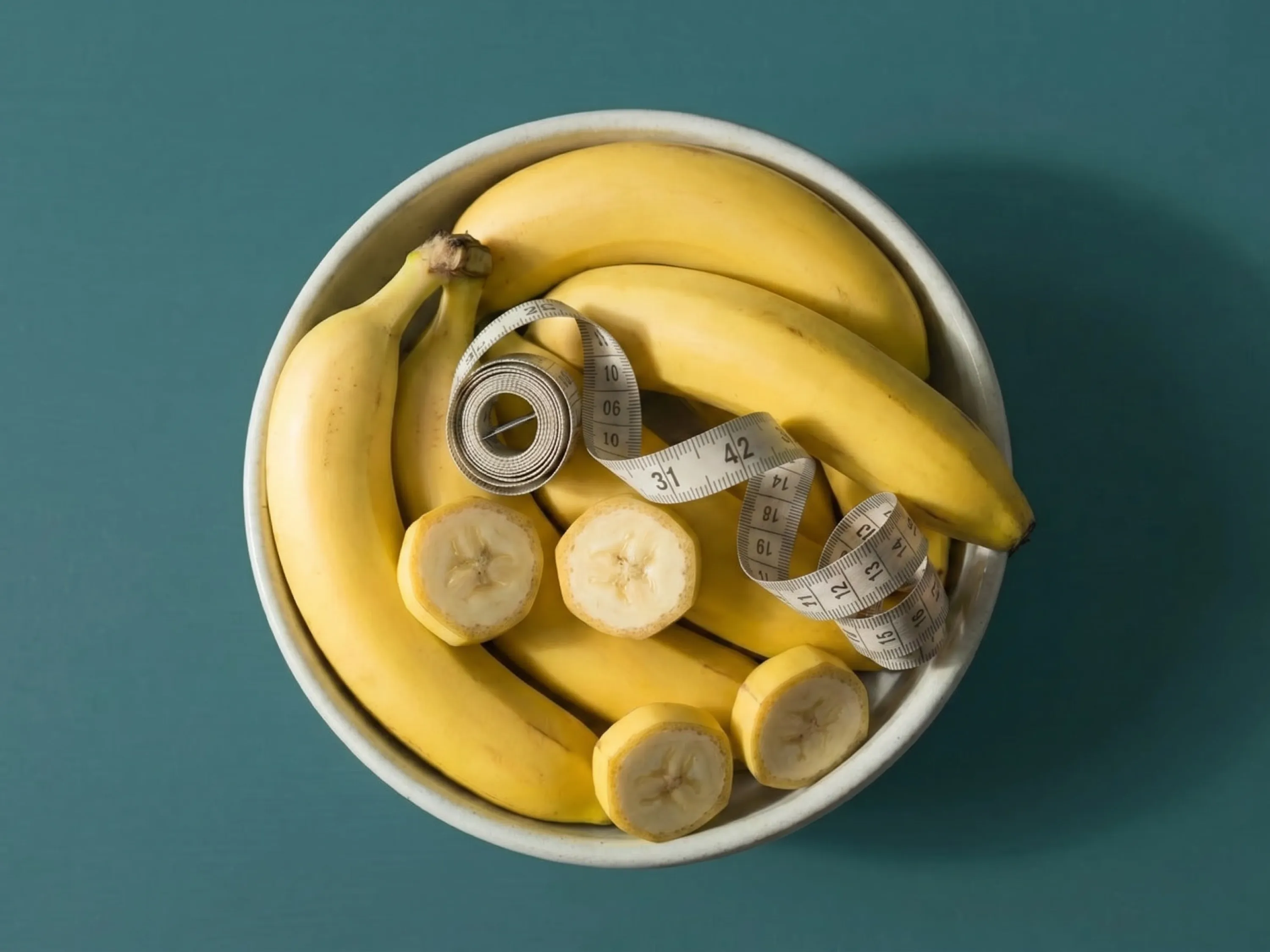 Eine Schale mit Bananen und einem Maßband verdeutlicht das Prinzip der Bananen-Diät.