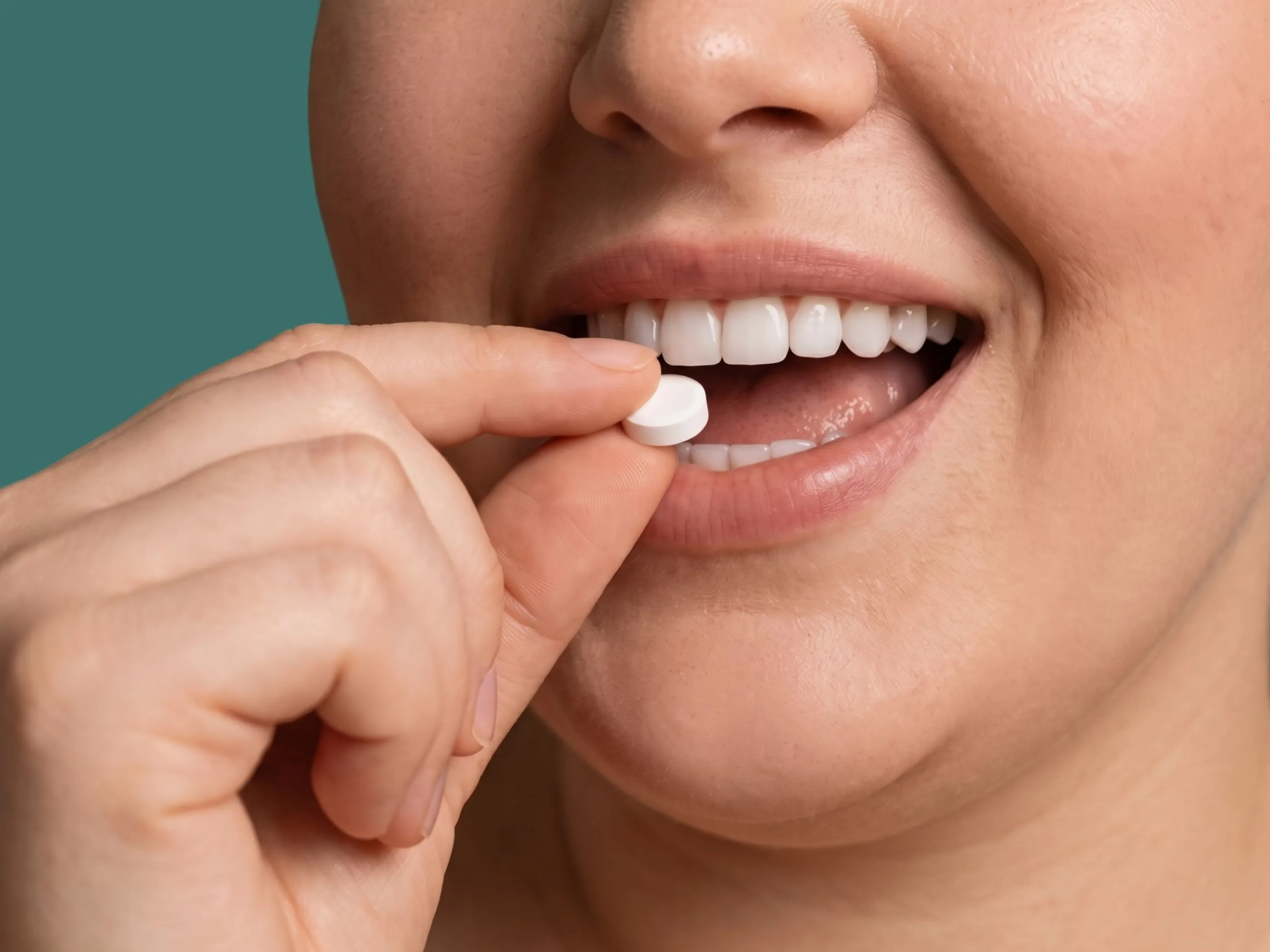 Person führt eine weiße Tablette zum Mund. Symbolbild für die Anwendung und Einnahme von Wegovy Tabletten. | GoLighter
