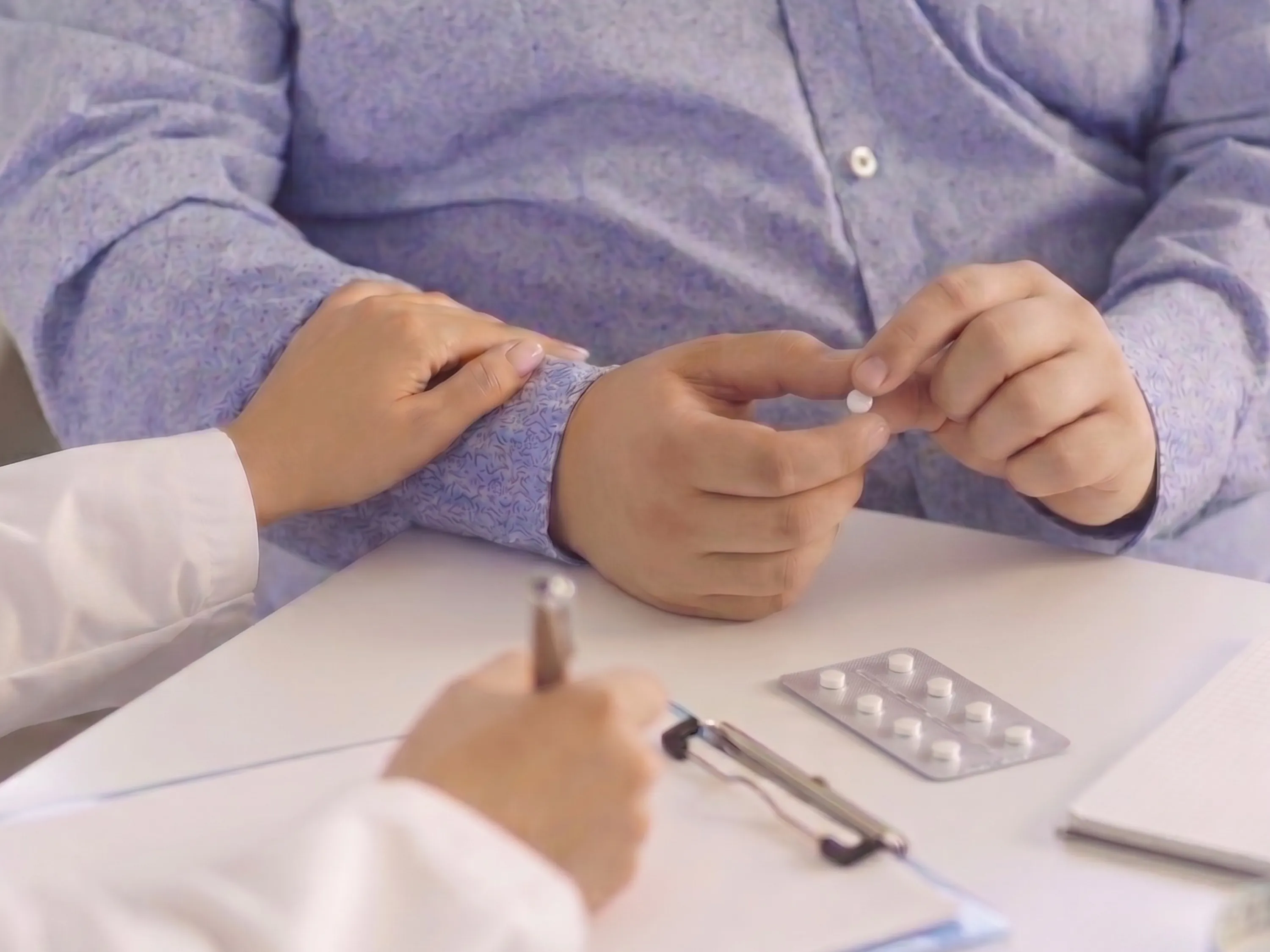 Patient hält eine weiße Tablette in der Hand, während ein Arzt den Arm fühlt und über die Nebenwirkungen der Wegovy Tablette aufklärt. | GoLighter