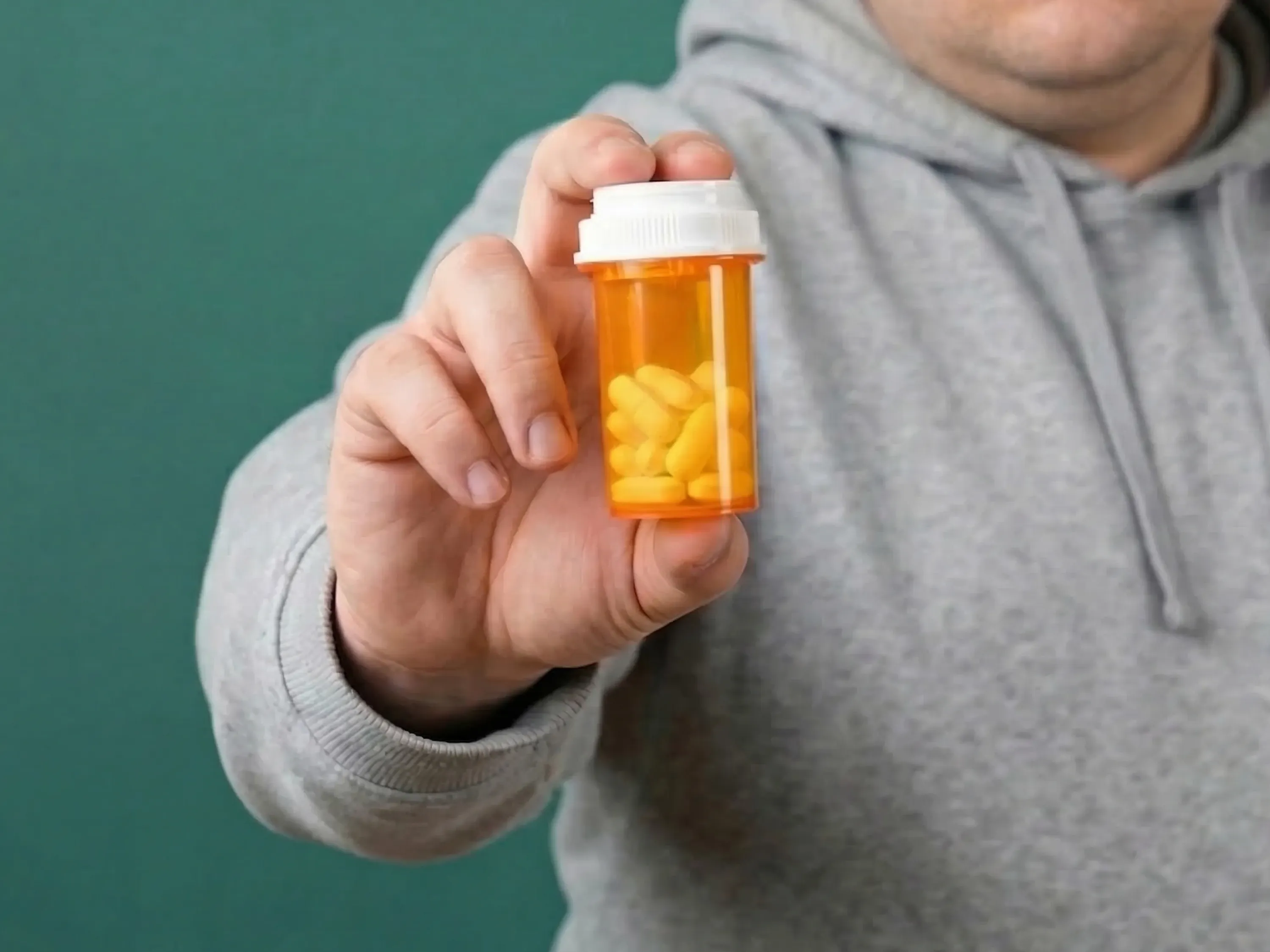 Abnehmen mit Abführmittel: Person hält eine orange Medikamentendose mit Tabletten in der Hand.