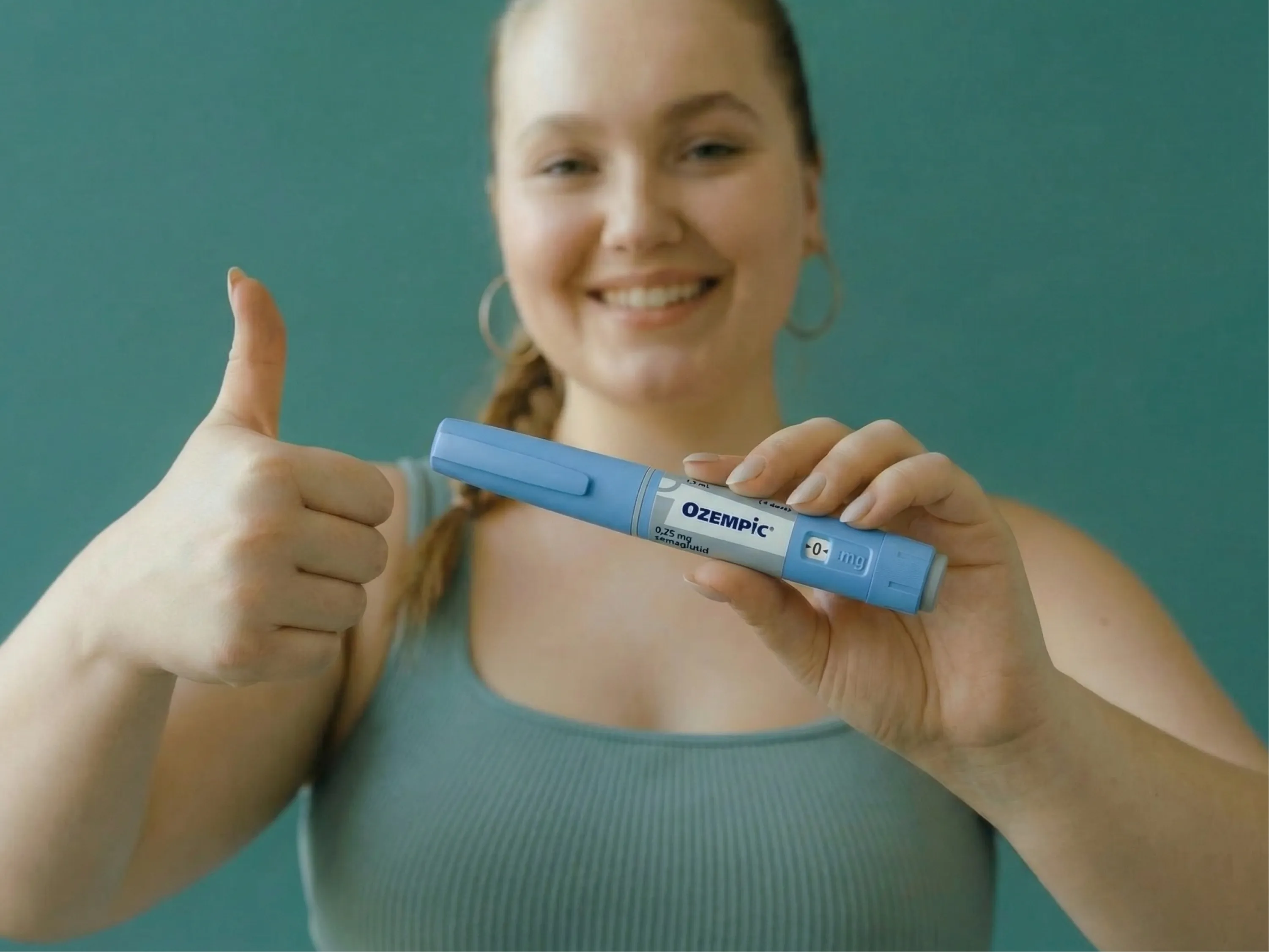 Lächelnde Person zeigt Daumen hoch und hält einen Ozempic®-Pen zur Ozempic® Zulassung.