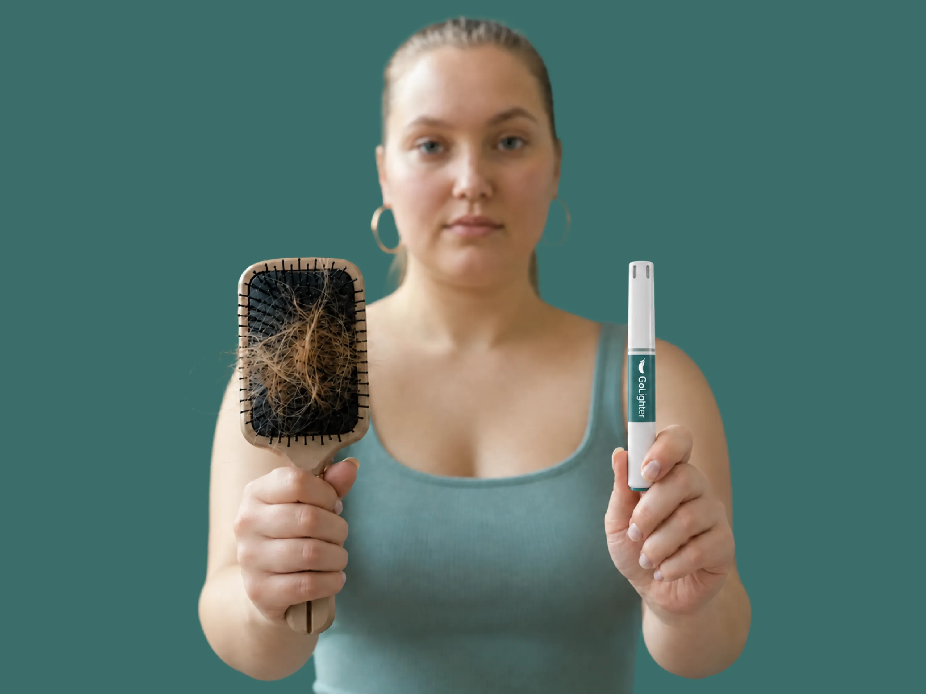Eine Frau hält eine Haarbürste voller Haare und einen Mounjaro 2,5 mg Pen vor grünem Hintergrund.