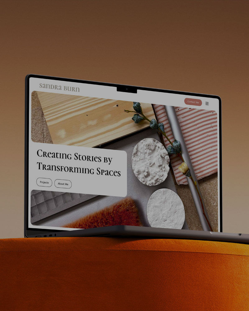 laptop on a sofa displaying the home hero header landing page view of sandra burns portfolio