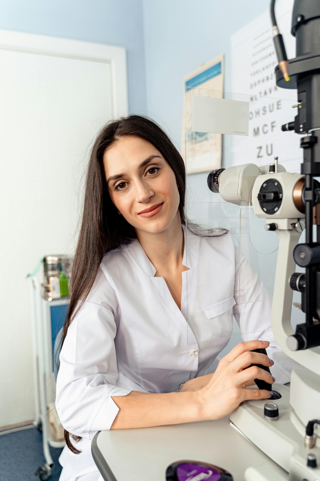 Optometrist in white coat standing next to eye examination equipment