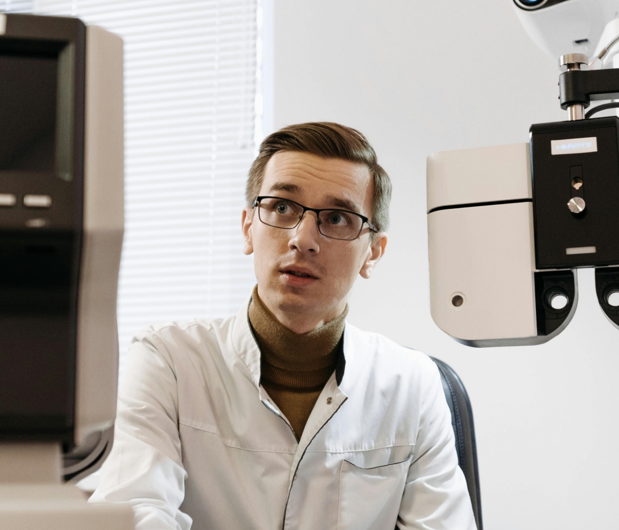 Professional in white lab coat sitting near medical equipment