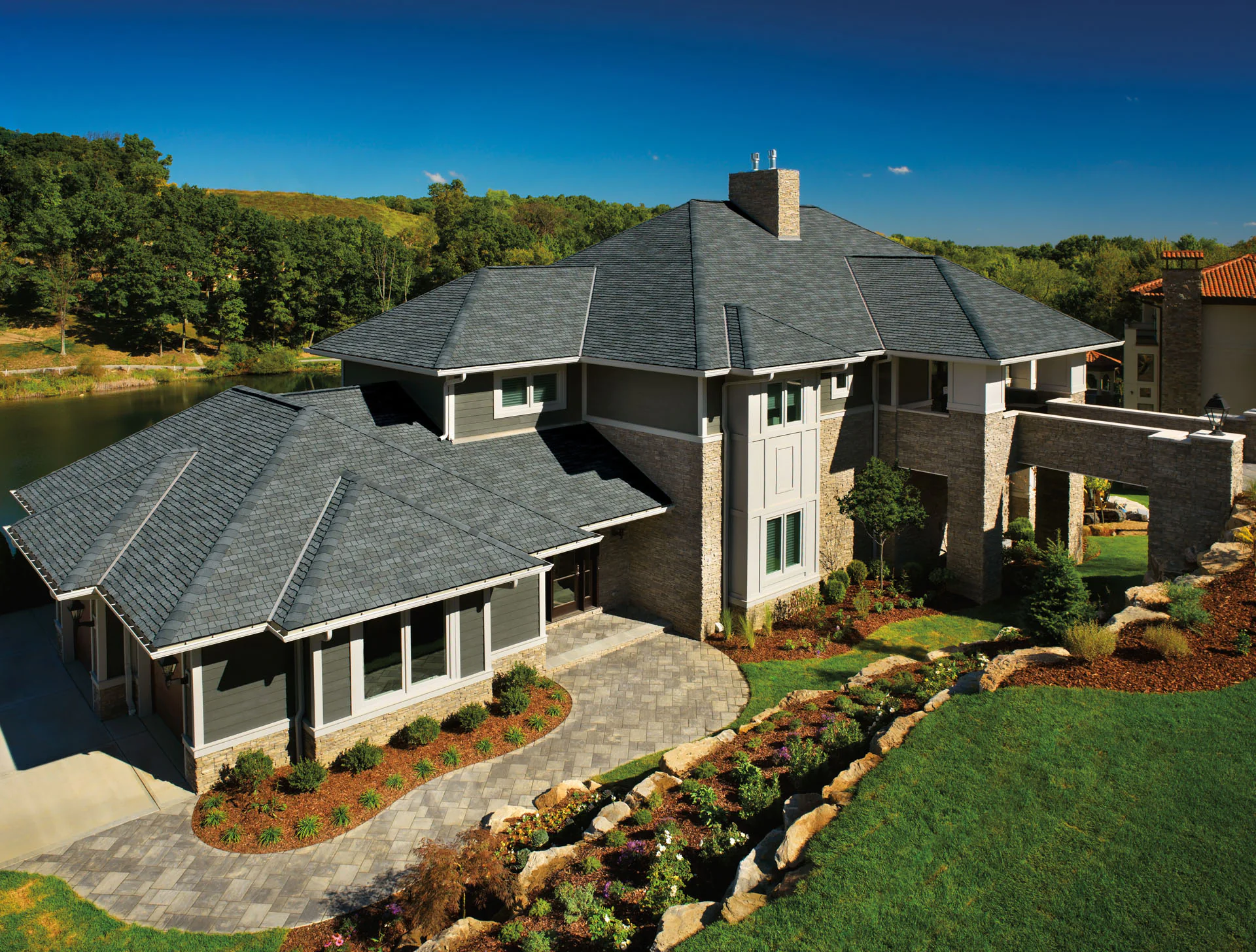 Aerial view of a lakeside home with a gray asphalt shingle roof