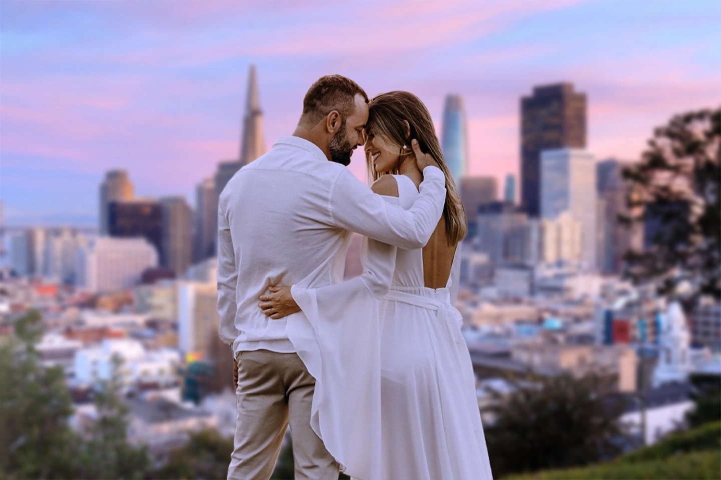 a man and woman in white dress kissing in front of the SF skyline
