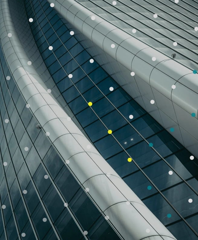 Curved modern glass and metal building facade with decorative colored dots overlay.