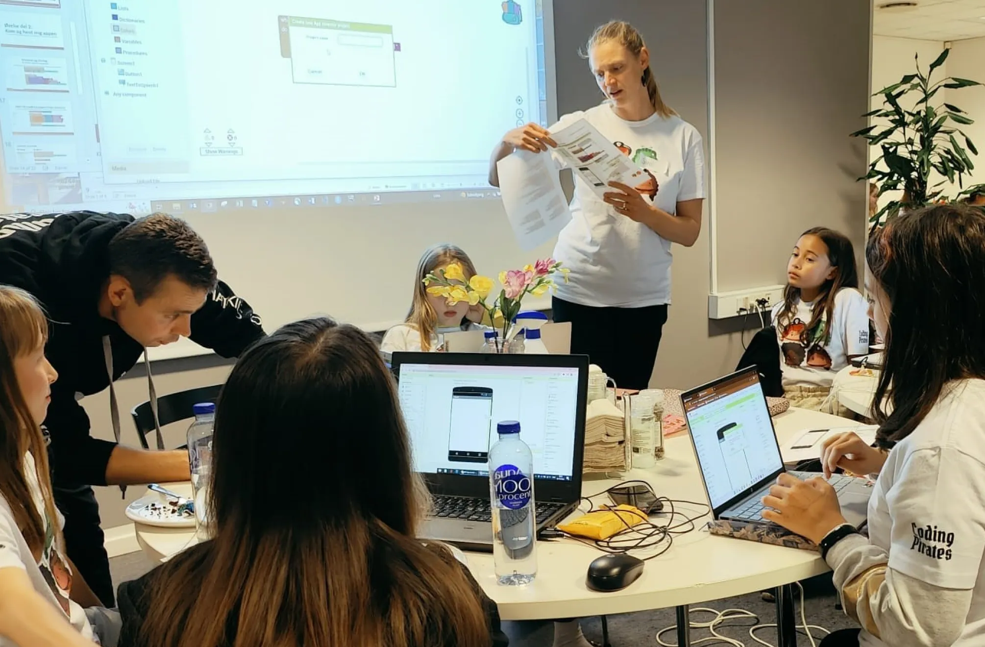 a group of people sitting around a table with laptops
