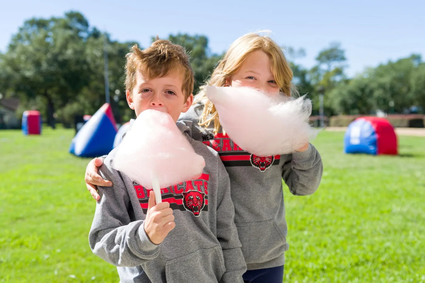 Kids enjoying cotton candy at a Freedom Fun fall festival with the laser tag arena behind them