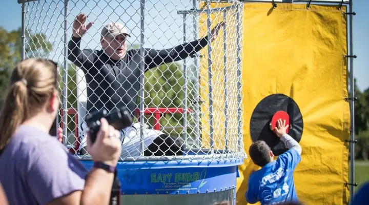 Kids dunking an adult in a dunk tank rental.