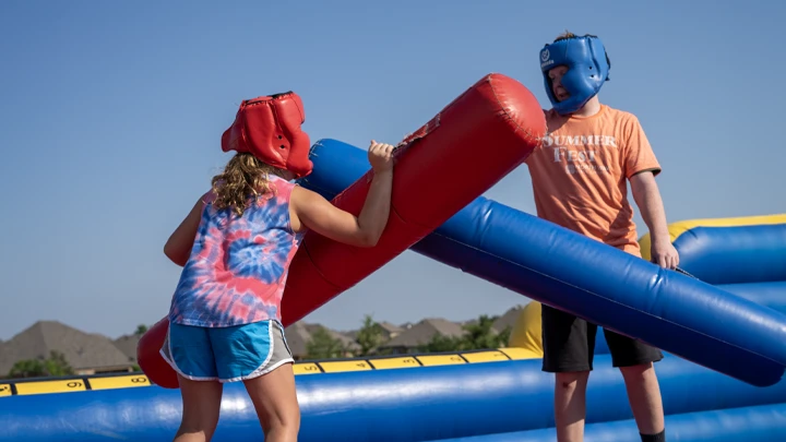 Two players battling on our inflatable joust rental.