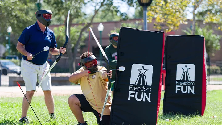Two adults playing archery tag at a corporate party