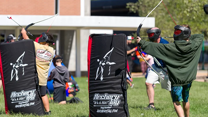 Teenagers playing with our archery tag equipment rental at a school event