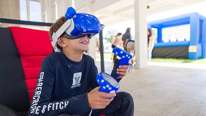 A kid playing with a vr headset outside at a vr party.