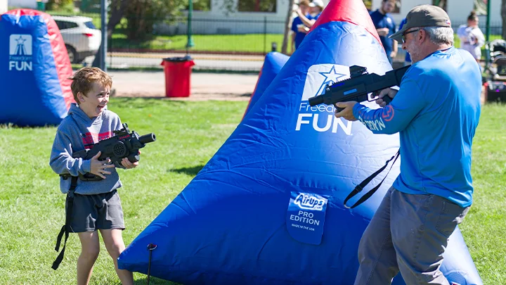 People enjoying an outdoor laser tag party at a school event. Our mobile laser tag rental packages are great for team builders, birthdays, school events & more.