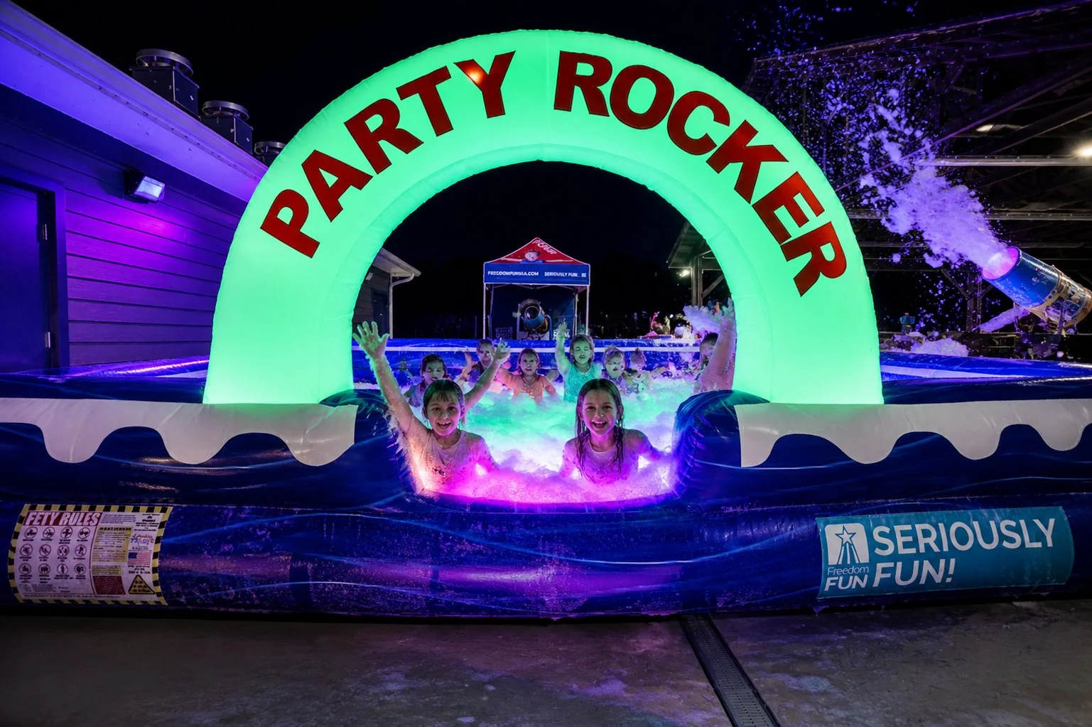 Kids cheering with hands up inside the LED-lit Party Rocker foam pit at a Winston-Salem NC night birthday party