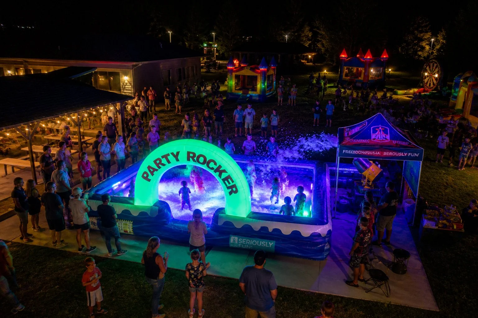 Crowd gathered around the LED-lit Party Rocker foam pit at a large evening community event in Winston-Salem NC