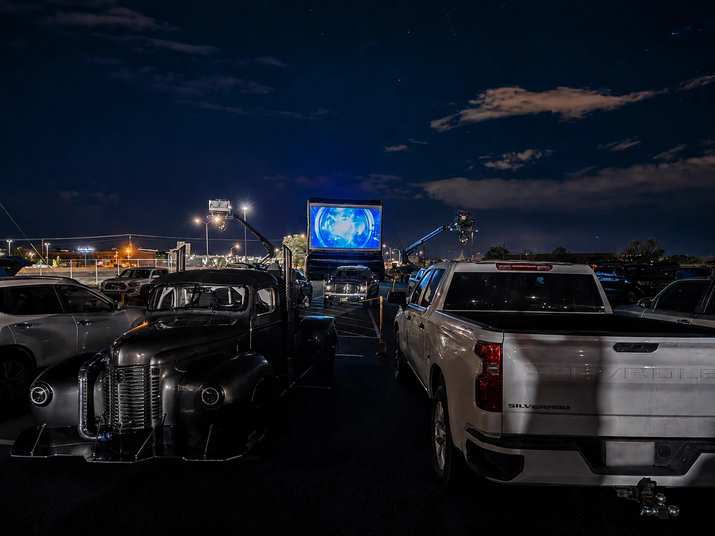 Freedom Fun USA giant outdoor movie screen rental at urban drive-in event with vintage truck and modern vehicles under starry night sky