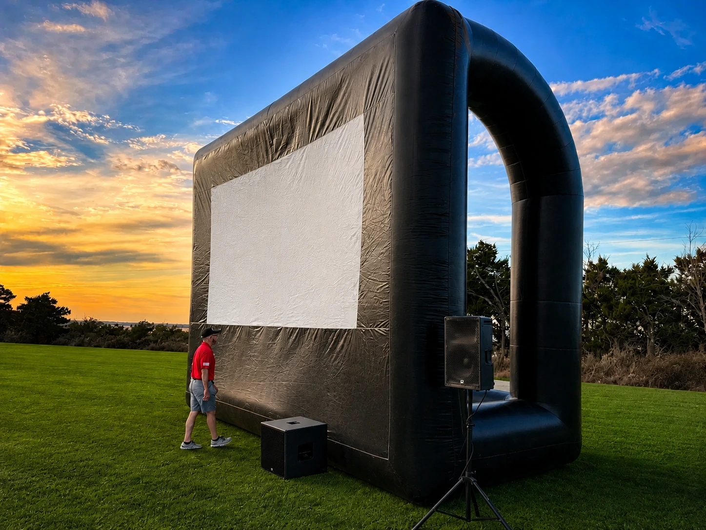 Freedom Fun USA 25ft Platinum outdoor movie screen rental Austin Texas with elevated viewable screen and premium subwoofer at golden hour sunset on green lawn