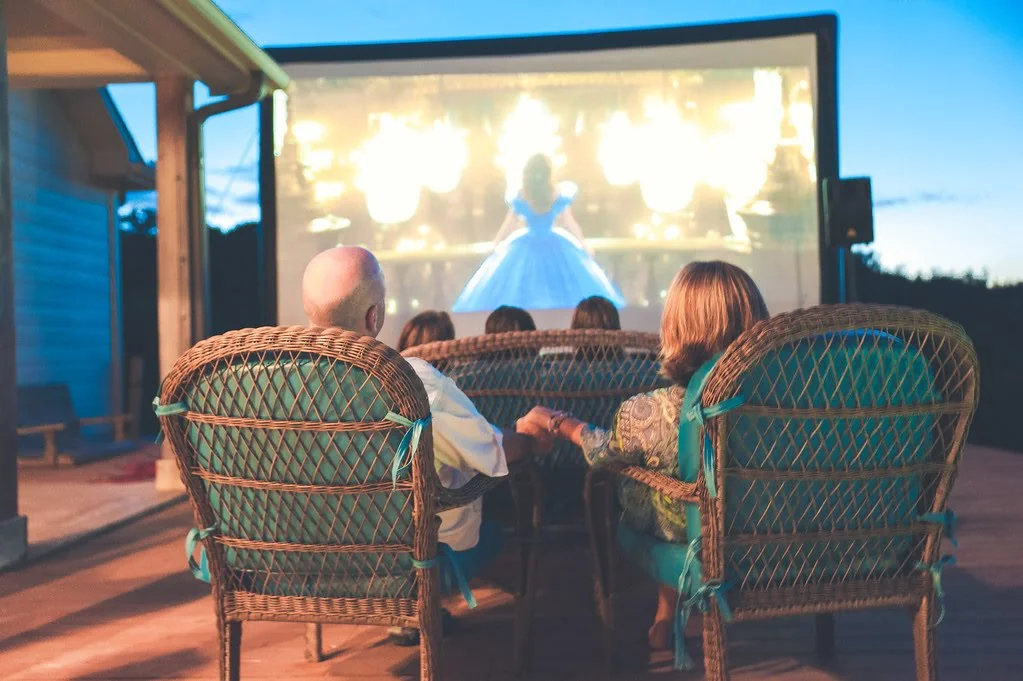 Family watching an outdoor movie on an inflatable screen at dusk