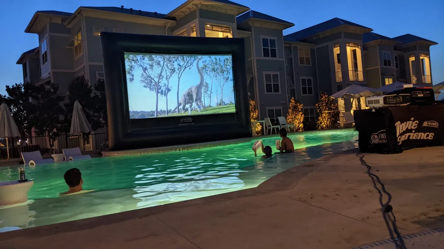 Kids watching a movie on an inflatable screen at a pool party at night