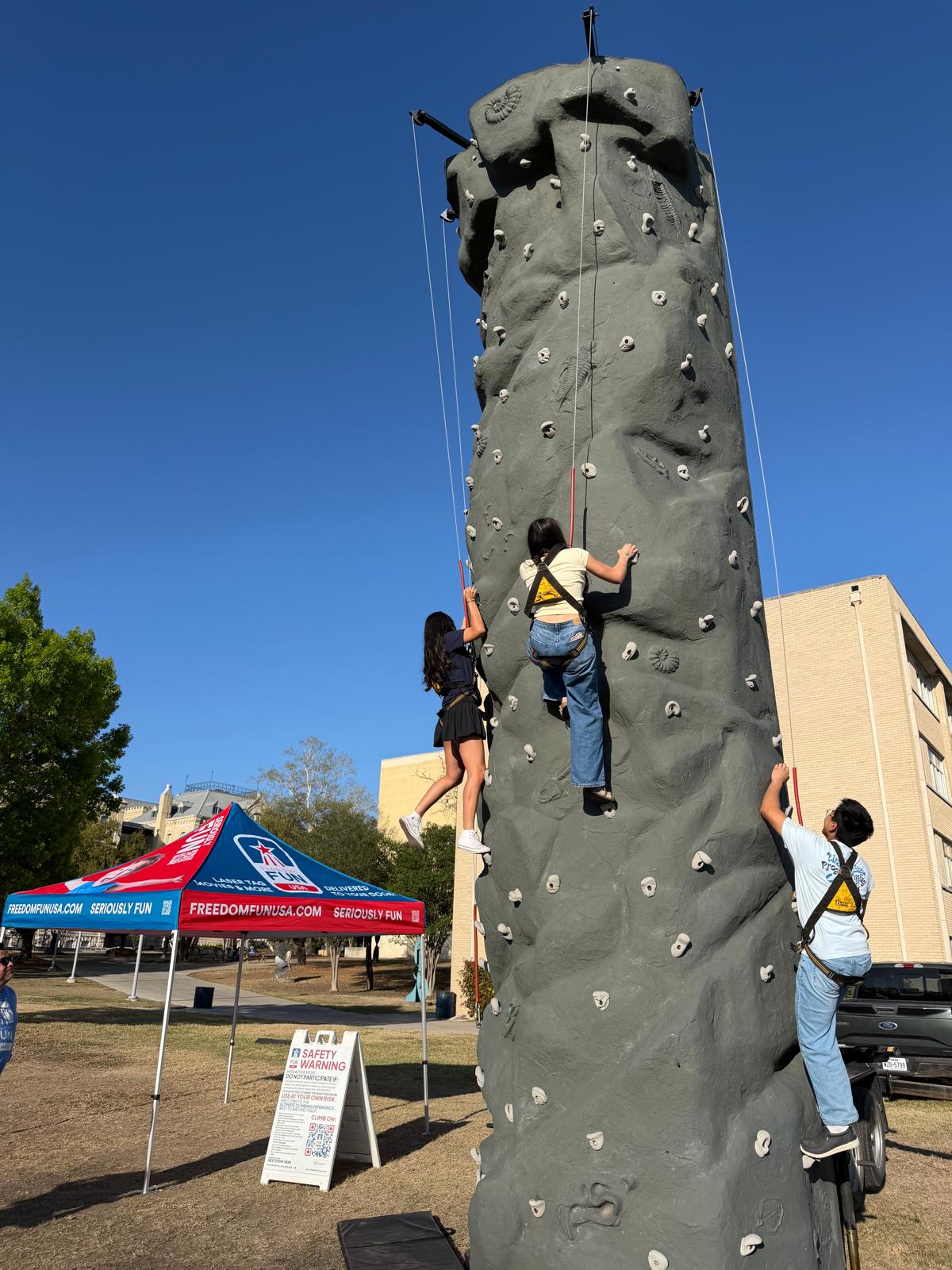 Kids climbing a portable rock wall rental at a school carnival.
