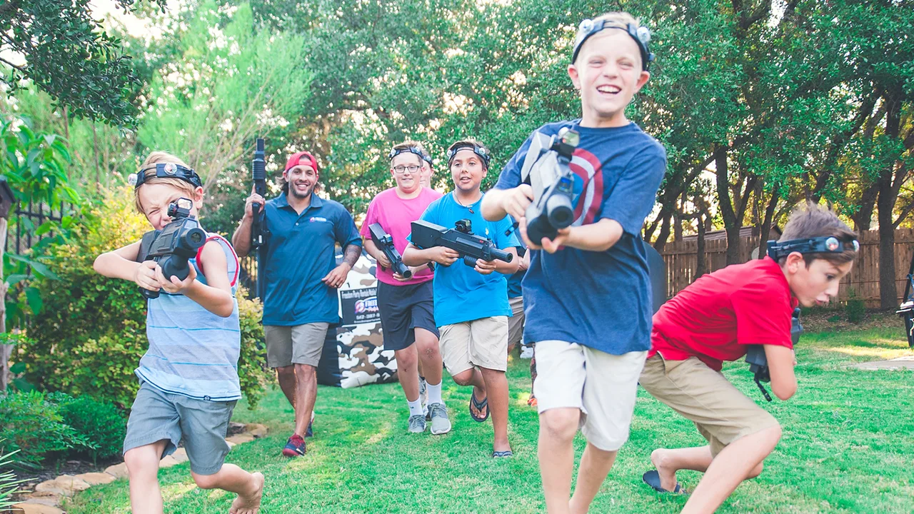 Kids playing mobile laser tag in a backyard with inflatable barricades