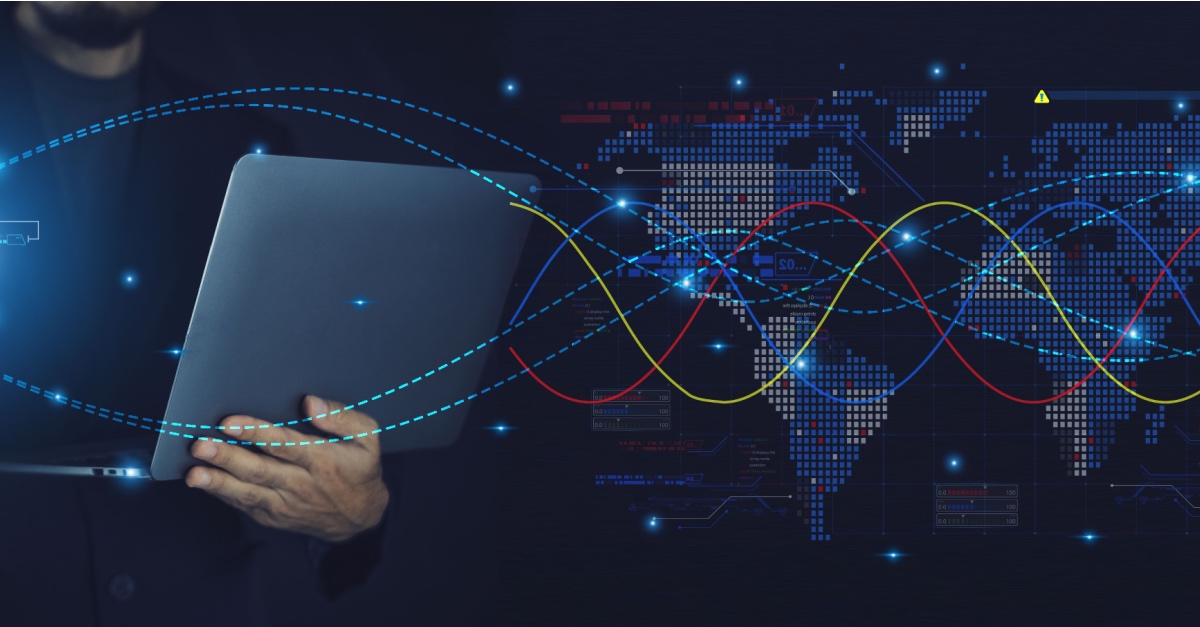 Person holding a laptop against a dark digital world map crossed by glowing data lines.