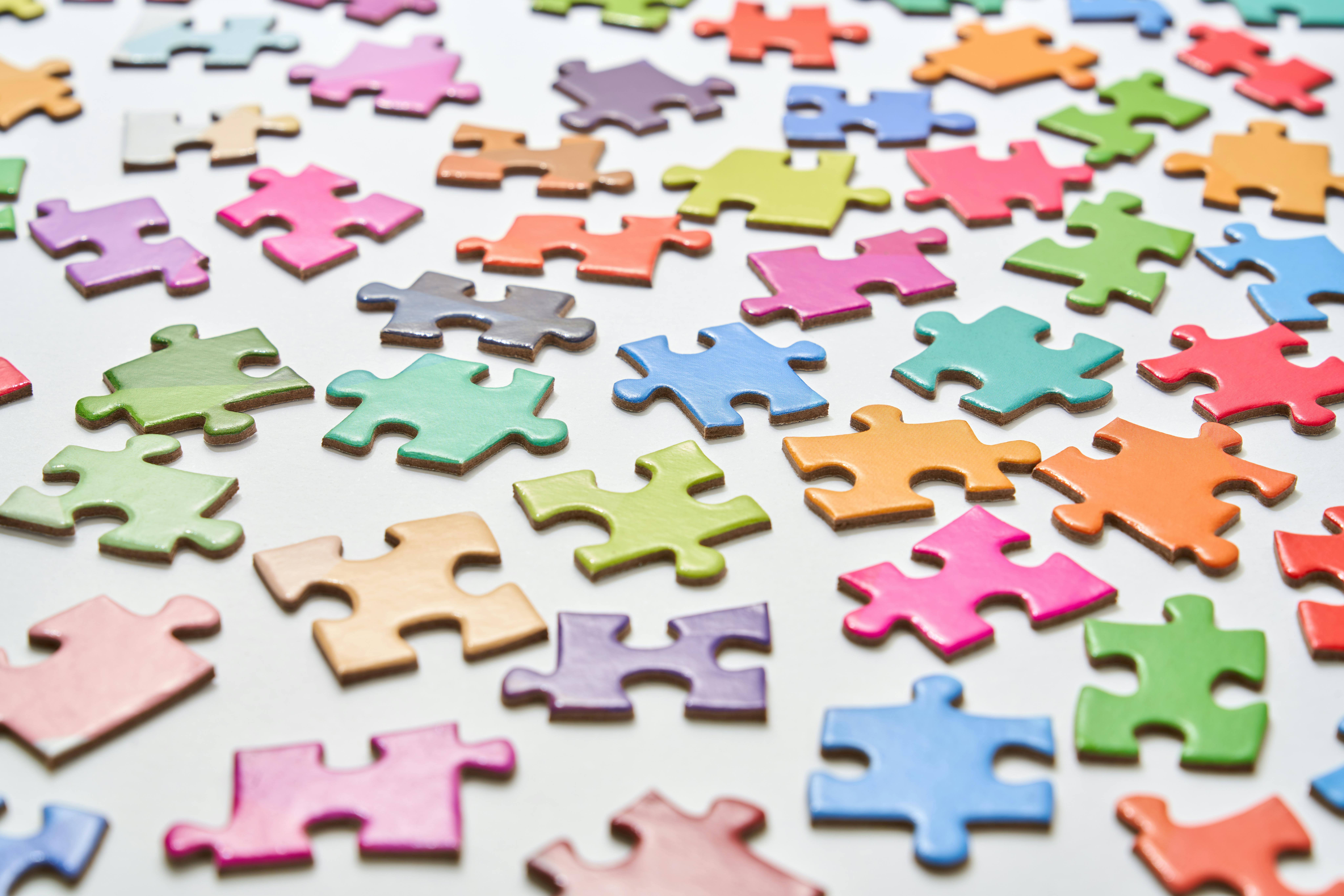 Scattered colorful jigsaw puzzle pieces on a white surface.