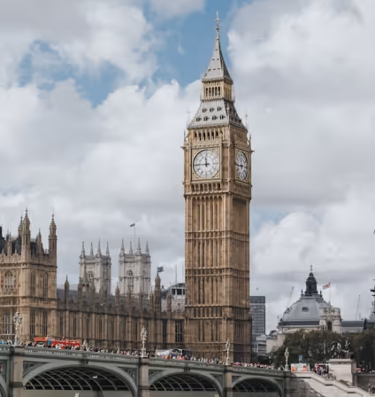 Big Ben clock tower and part of the Palace of Westminster in London with a cloudy sky backdrop.