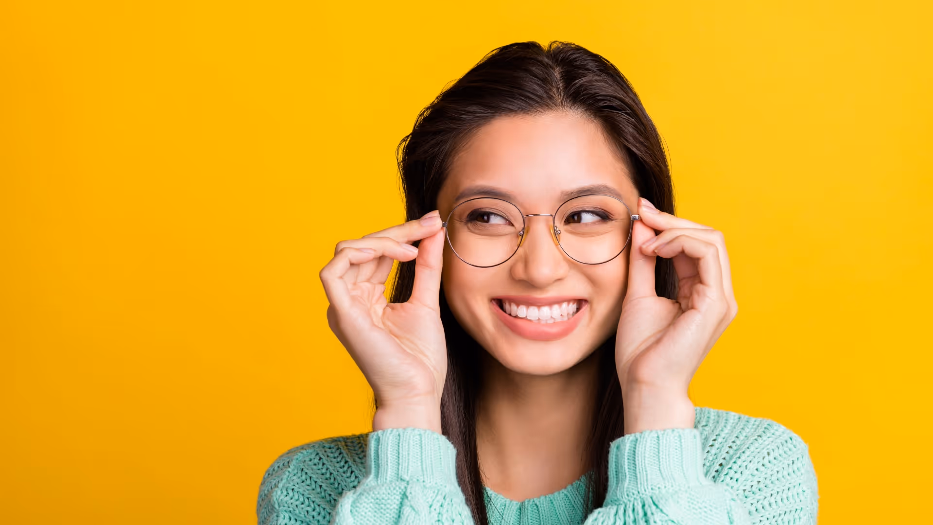 Woman holding up eyeglasses to her face and smiling