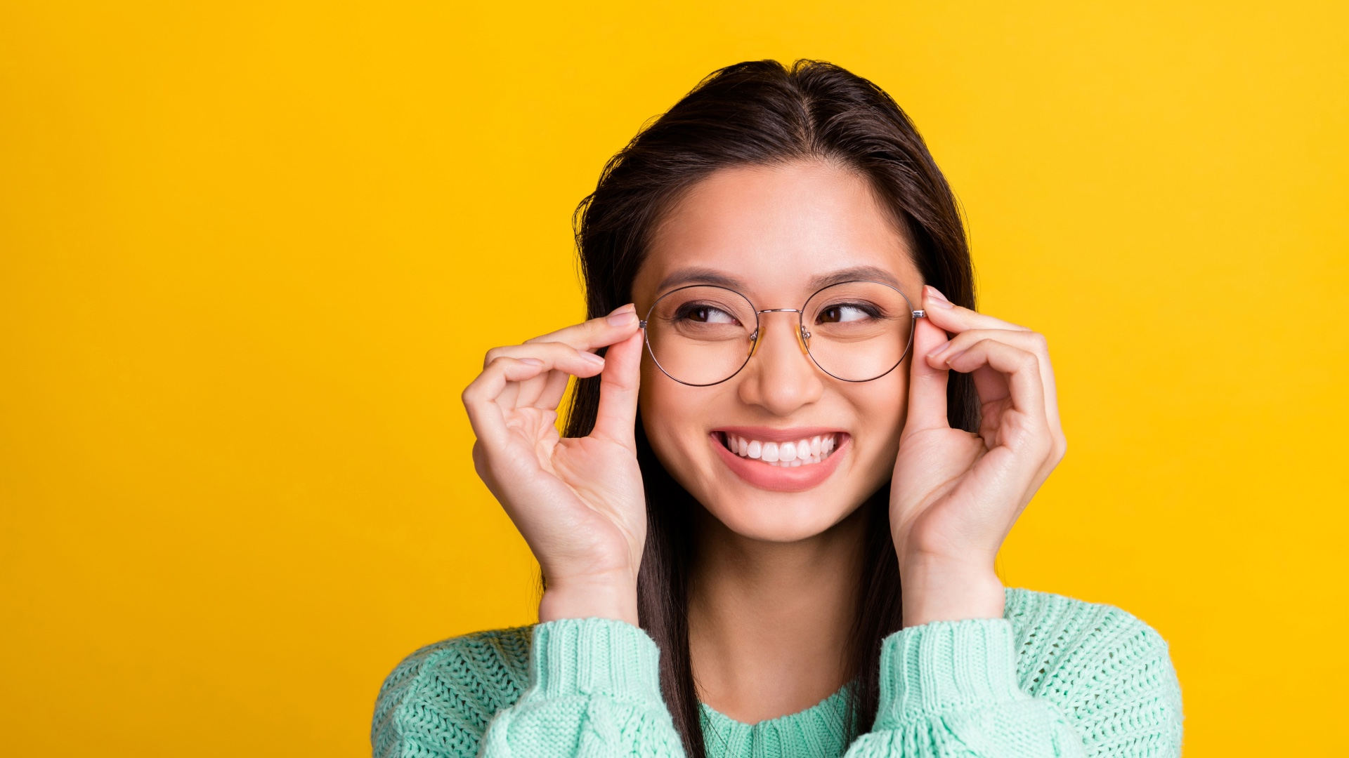 Woman holding up eyeglasses to her face and smiling