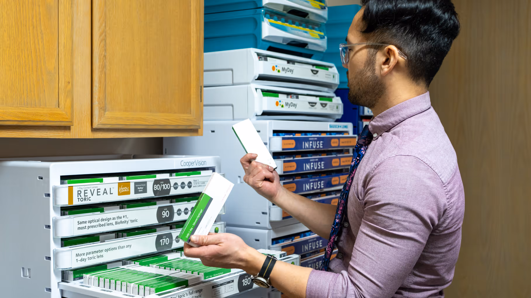 Dr. Jin arranging small individual contact lens boxes in a dedicated storage shelf at Vision Care Center