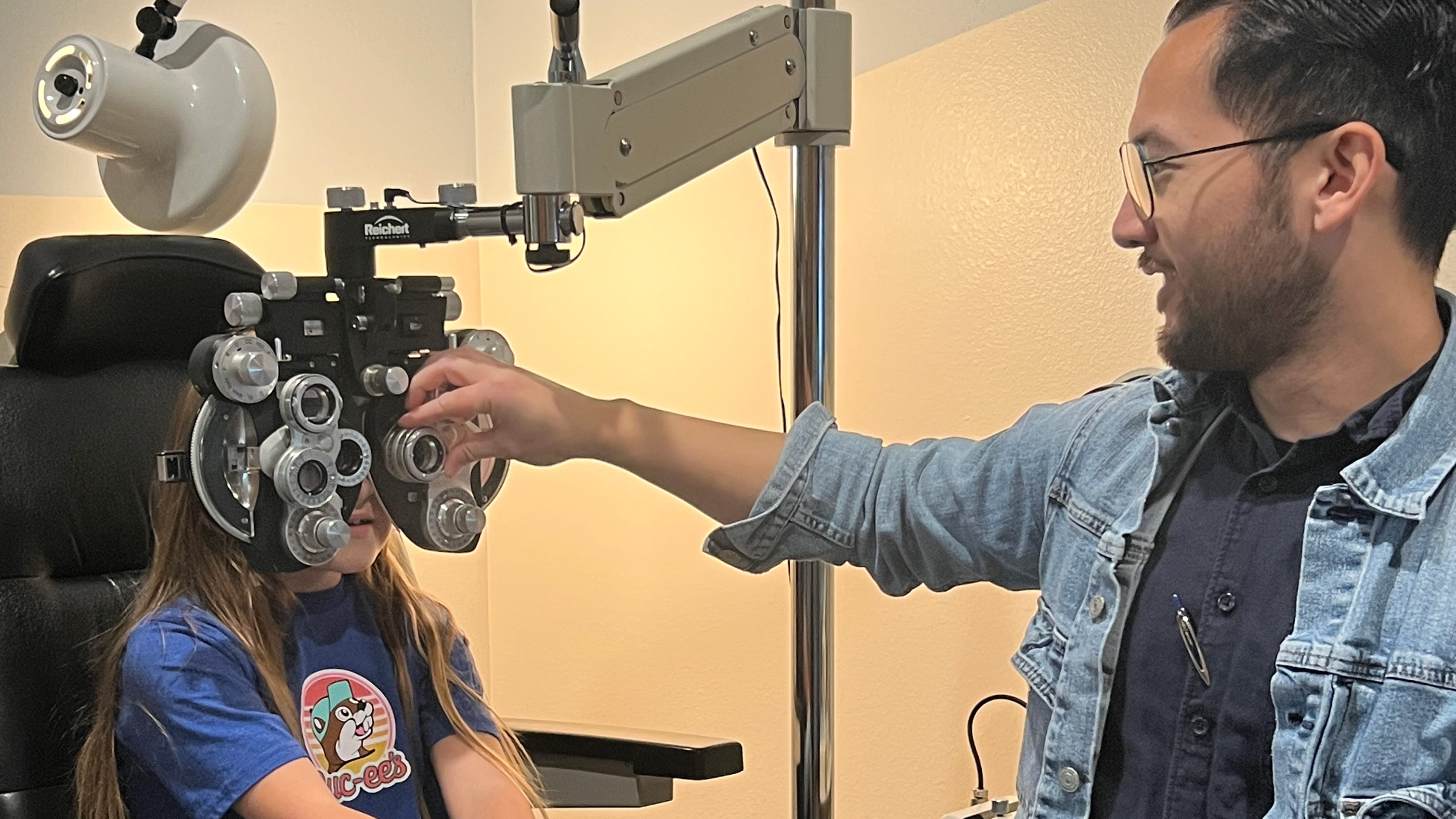Dr. Jordan Jin adjusting the phoropter lenses during a child's eye exam at Vision Care Center in Bellevue