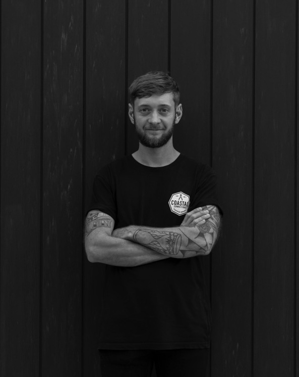 Director Joe Kelly standing against timber wall