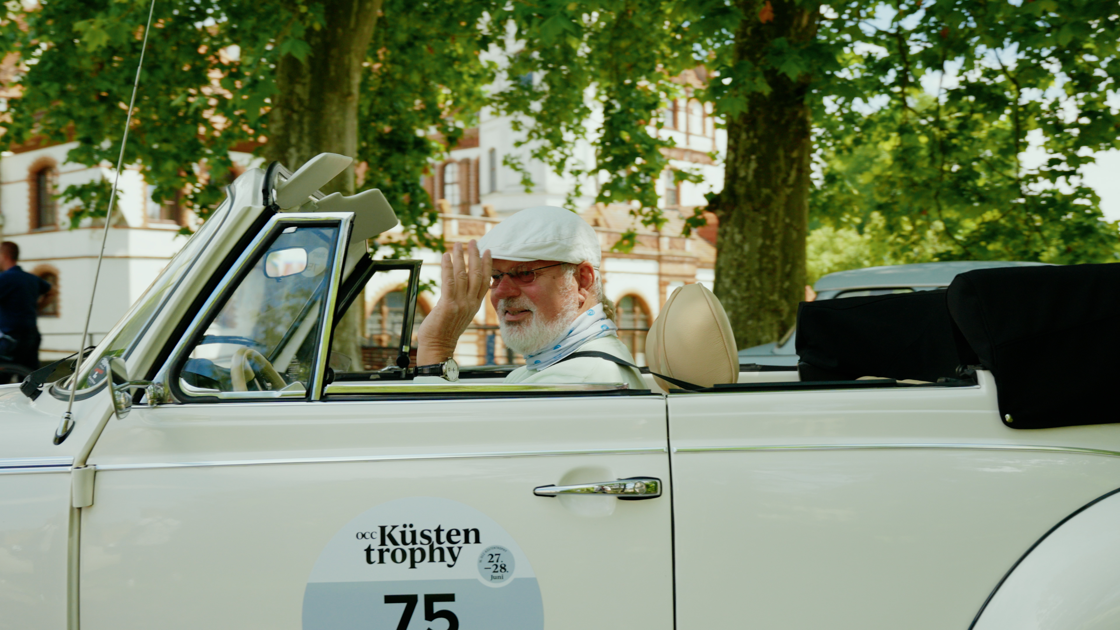 Mann winkt aus einem Oldtimer raus