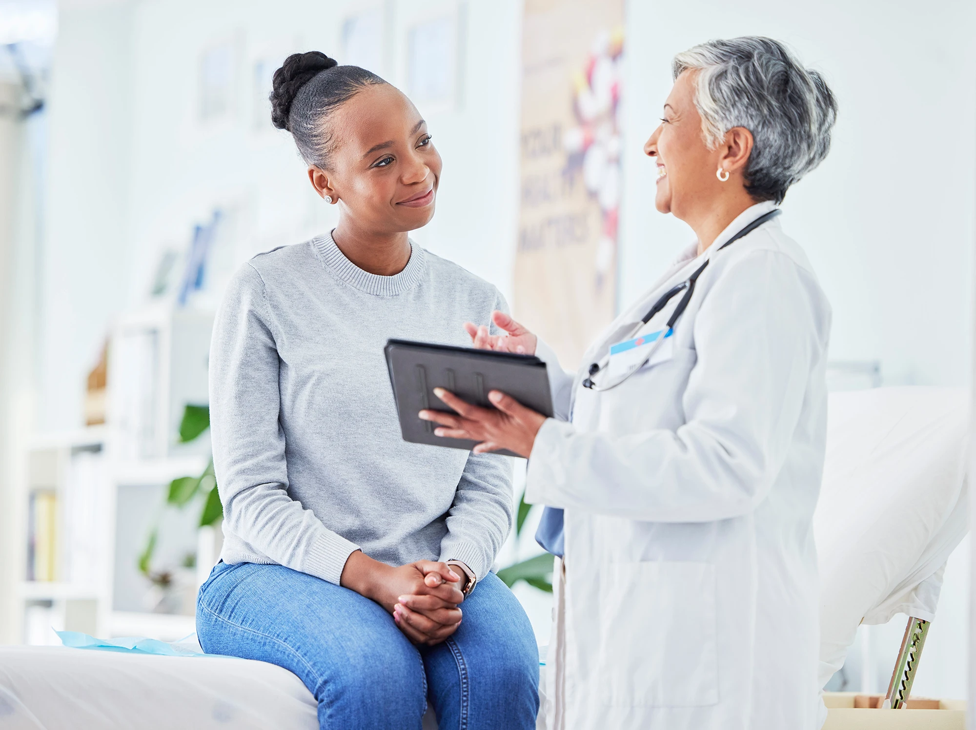 A female doctor holding an ipad explaining something to a female patient