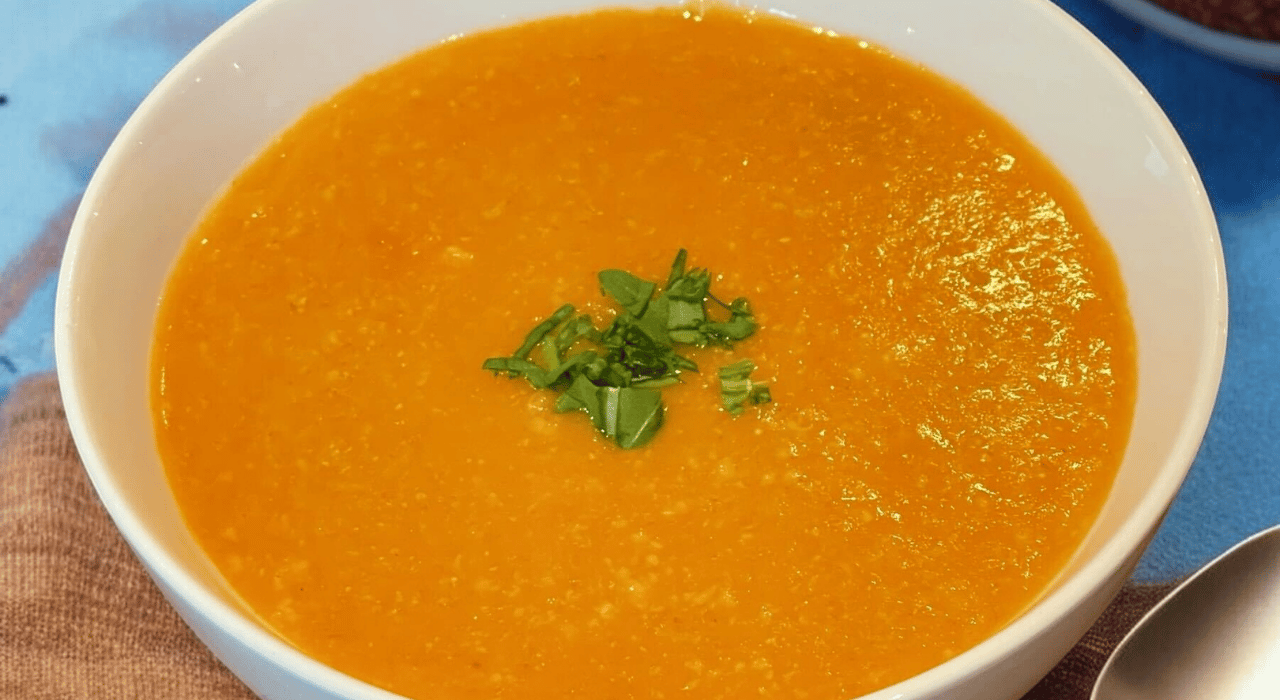 Hearty pumpkin, oat, and cumin soup in a bowl, smooth and golden, topped with parsley