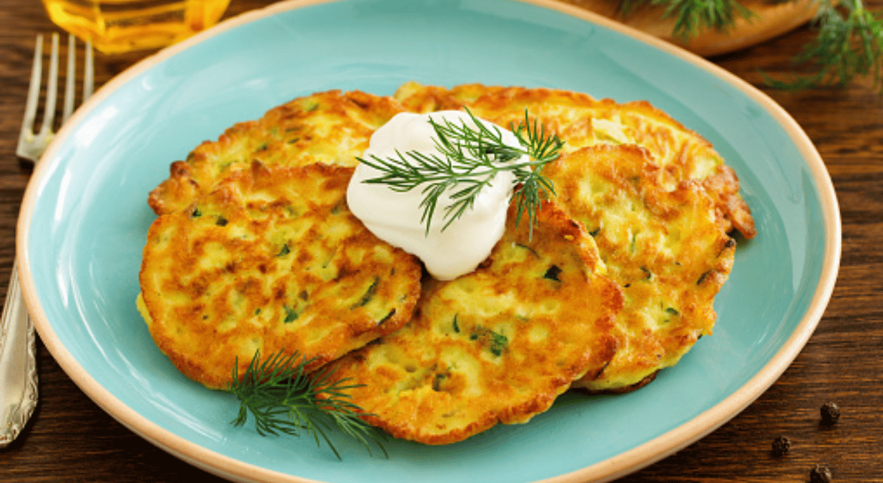 Zucchini pancakes on a plate with a dollop of sour cream on top