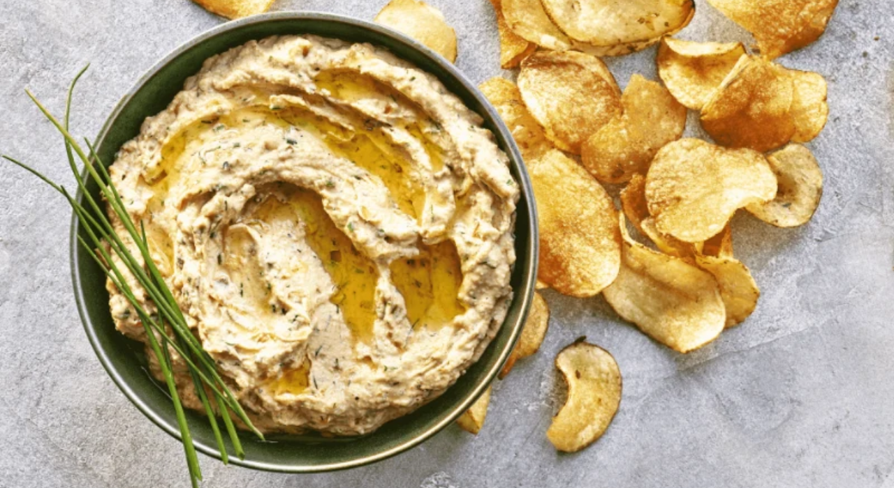 Caramelized onion dip in a bowl next to chips artfully strewn about.